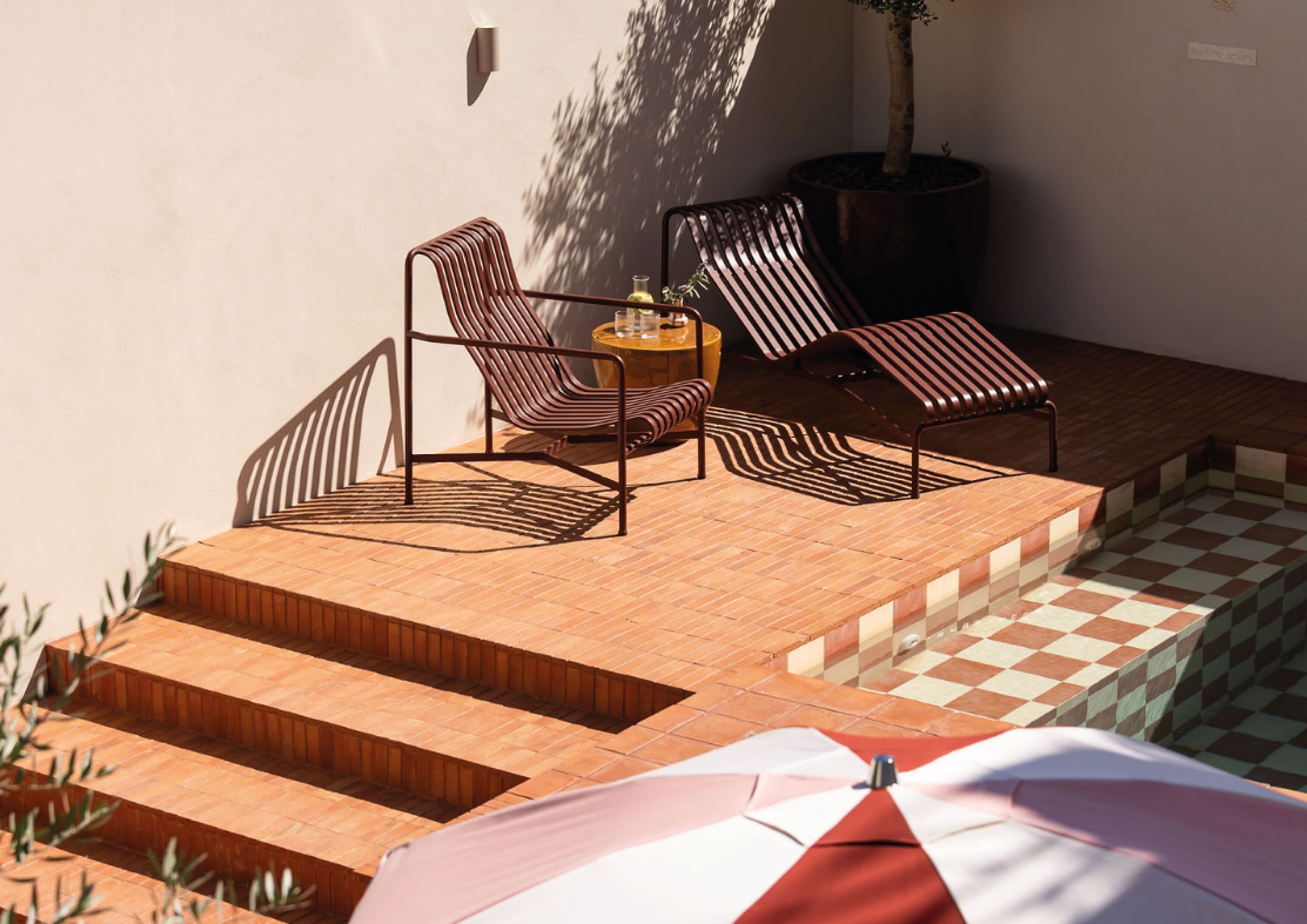 A patio with a checkered floor, a small round table, and striped chairs.