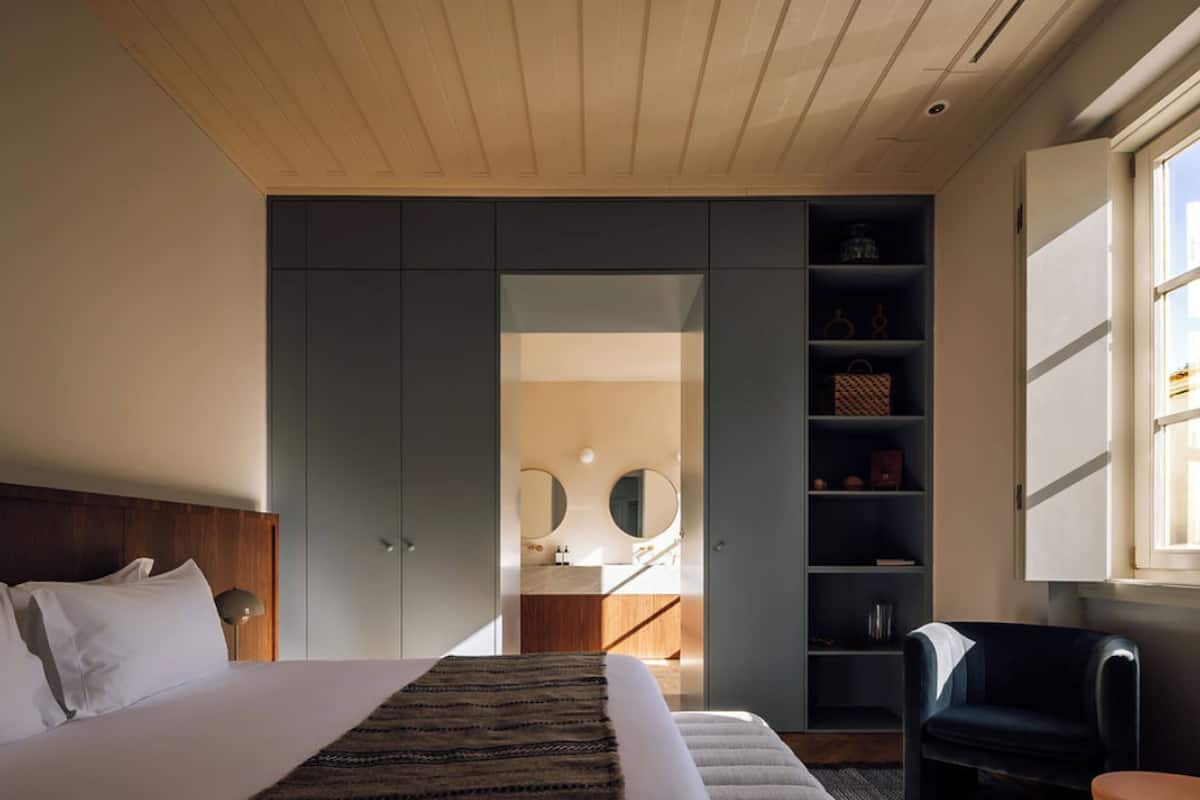 Ein modernes Schlafzimmer mit einem großen Bett, einem Kleiderschrank, einem Spiegel und einer Sitzecke.