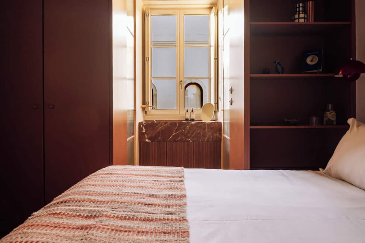 Ein Hotelzimmer mit einem Bett, einem Badezimmer mit Spiegel und einem Ablagebereich für Toilettenartikel.