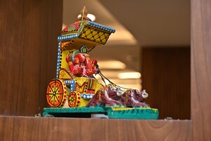 Une maquette miniature aux couleurs vives représentant un attelage traditionnel, avec des motifs complexes et une figurine assise à l’avant.