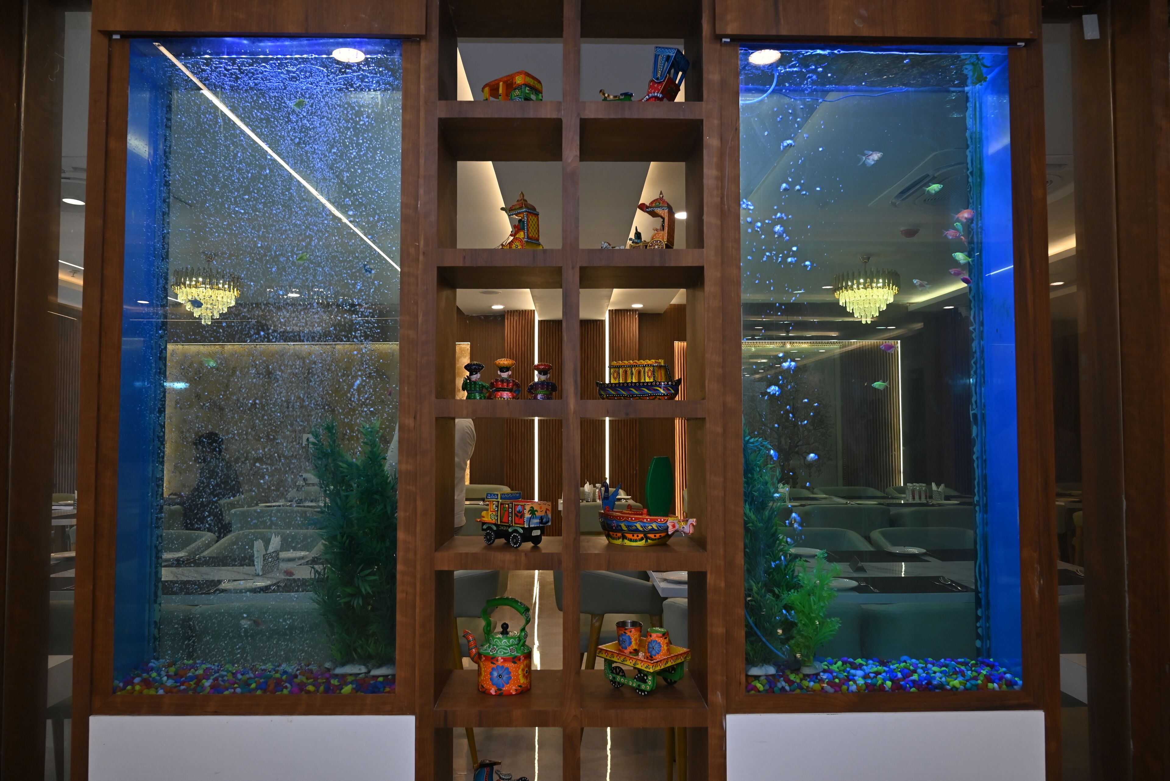 A wooden display cabinet with shelves containing various decorative items and a small aquarium.