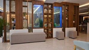 A modern lobby with a reception desk, seating areas, and decorative wooden panels with shelves. - EcoXpress Satva Varanasi - Vegetarian with all Options (Varanasi)