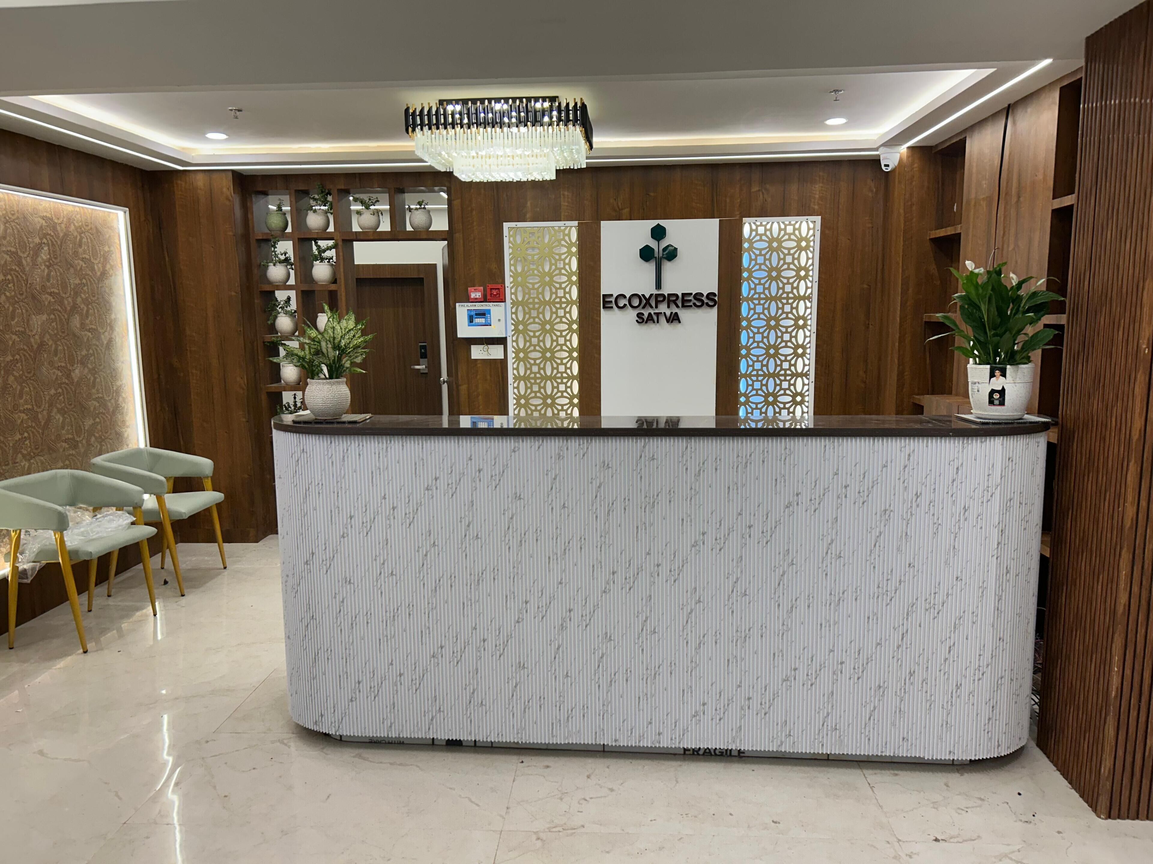A reception desk with a chandelier, potted plants, and a sign for 'ECOEXPRESS SATVA'.