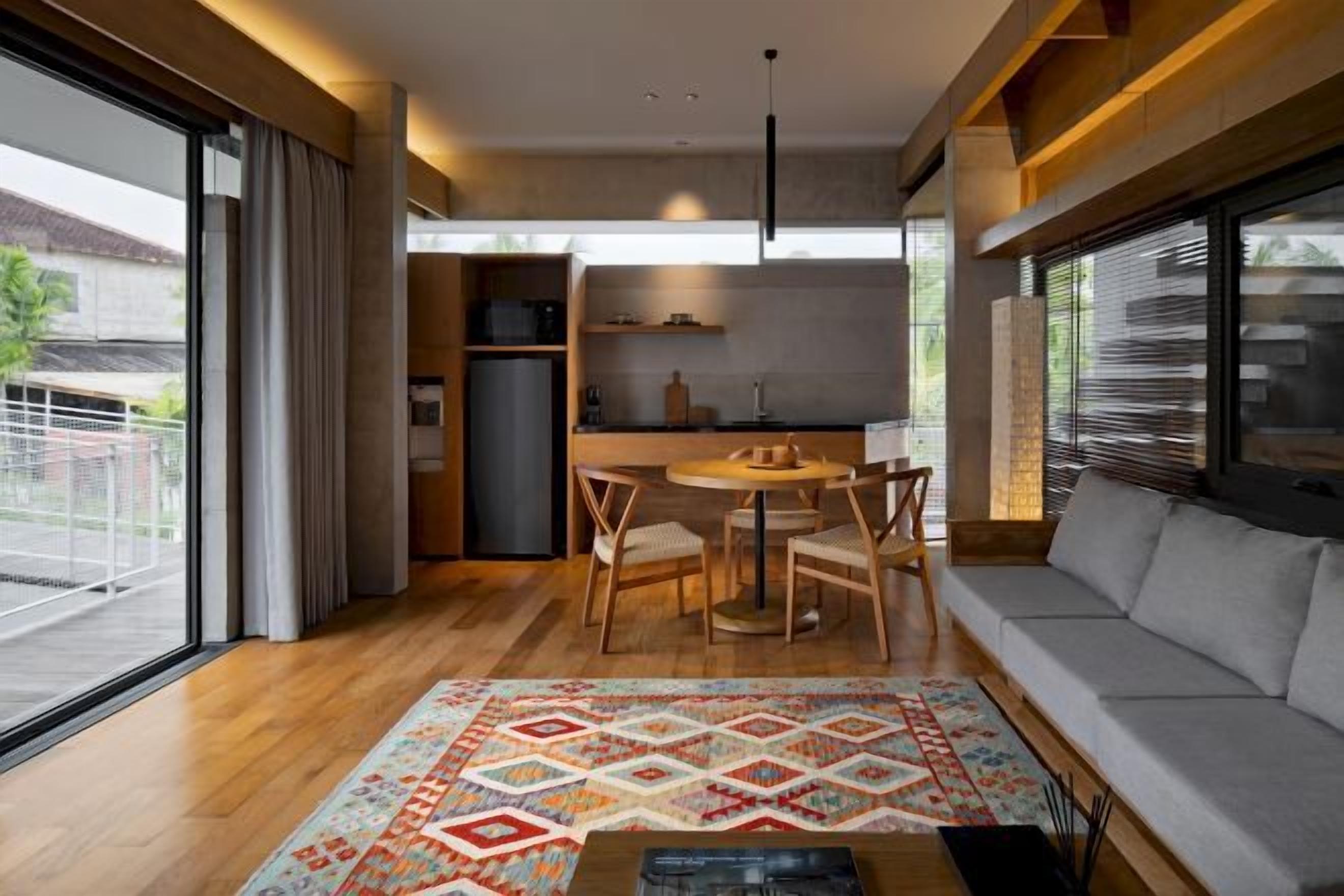 A modern living room with a sofa, a coffee table, and a dining area with chairs and a table.