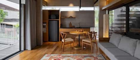 A modern living room with a sofa, a coffee table, and a dining area with chairs and a table.