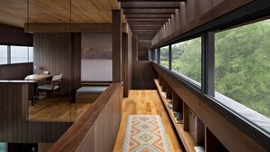 A modern interior with a long wooden bench, a desk, and a large window offering a view of greenery. - Villa Tana Takah (Bali)