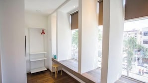 A room with a built-in bench along a window, a wooden floor, and a white door with a red object on it. - Paradise Suite @ Asia City (Kota Kinabalu)
