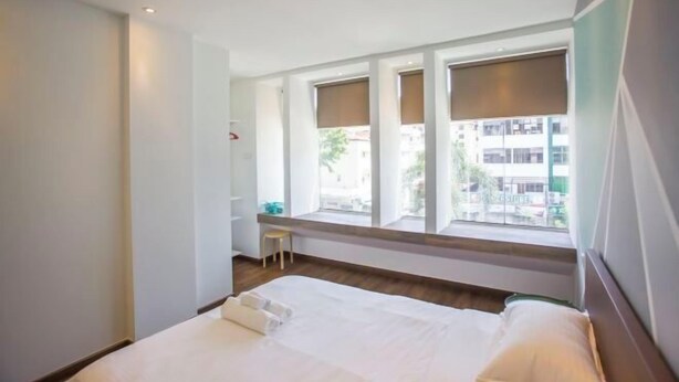 A hotel room with a bed, a small stool, and large windows. - Paradise Suite @ Asia City (Kota Kinabalu)