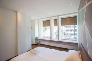 A hotel room with a bed, a small stool, and large windows. - Paradise Suite @ Asia City (Kota Kinabalu)