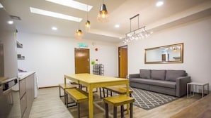 A modern kitchen with a dining table and benches, a gray sofa, and a patterned rug. - Paradise Suite @ Asia City (Kota Kinabalu)