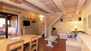 Un espace de vie avec un plancher en bois, comprenant une table à manger, des chaises, un canapé et un téléviseur.