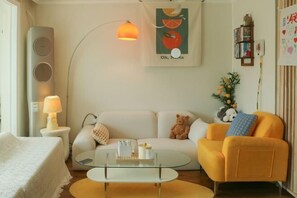 A modern living room with a sofa, armchair, coffee table, and a lamp.