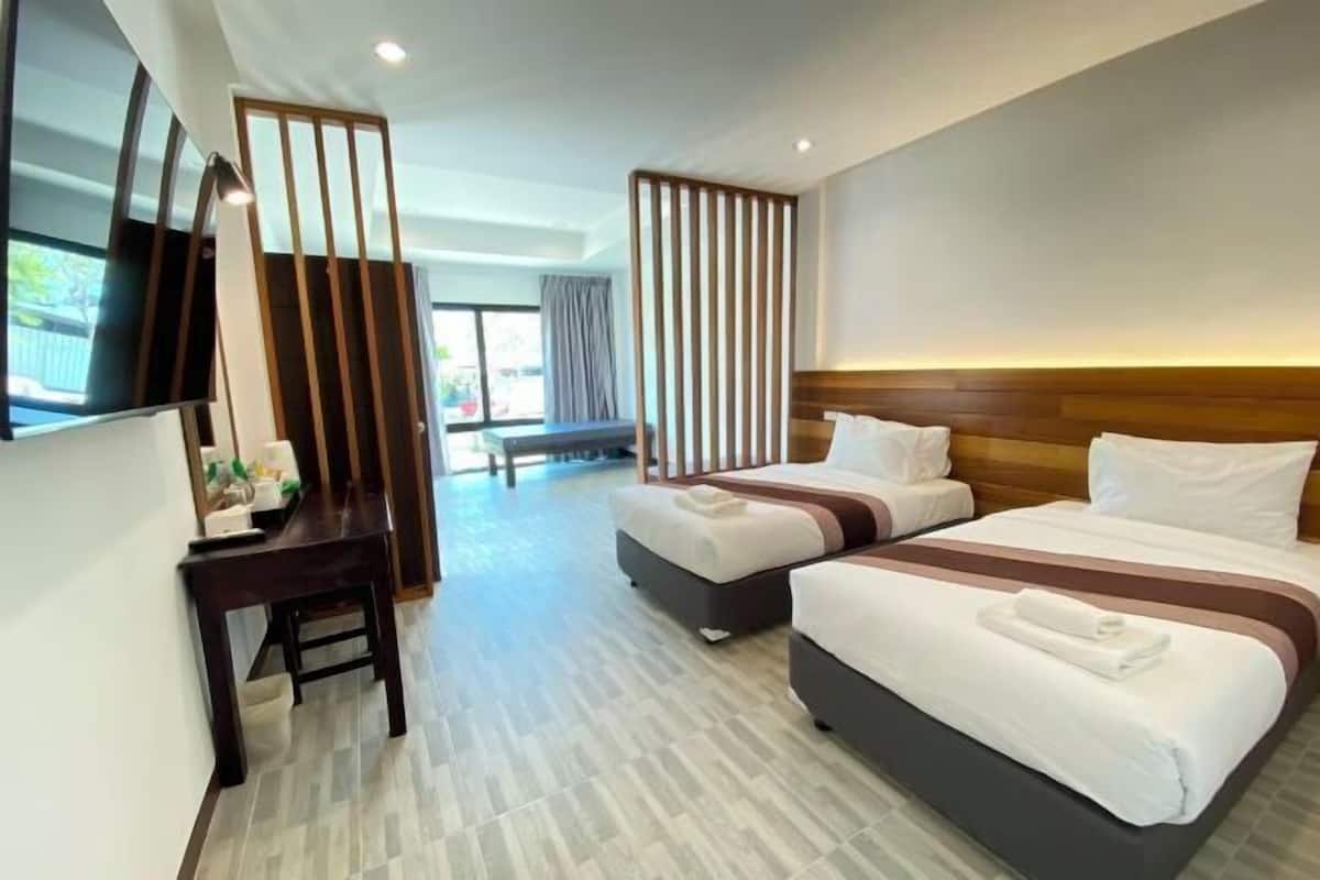 A hotel room with two beds, a desk, a TV, and a view of the outdoors.