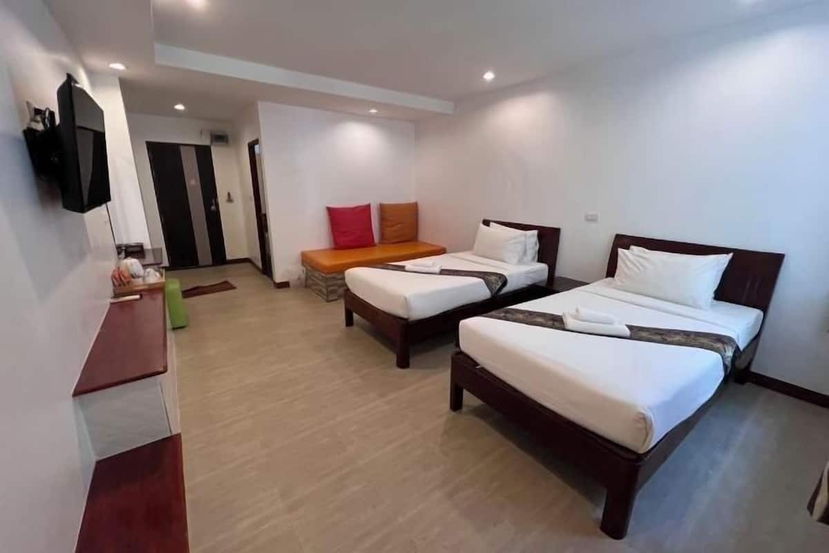 A hotel room with two beds, a TV, a desk, and a door leading to another room.
