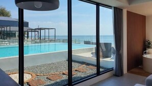 A modern hotel room with large windows, a view of a pool, and a private bathroom. - Rattanapura (Tha Mai)