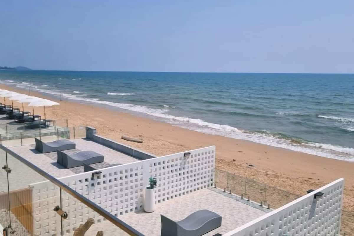 A beachside hotel with a terrace, seating, and a view of the ocean.