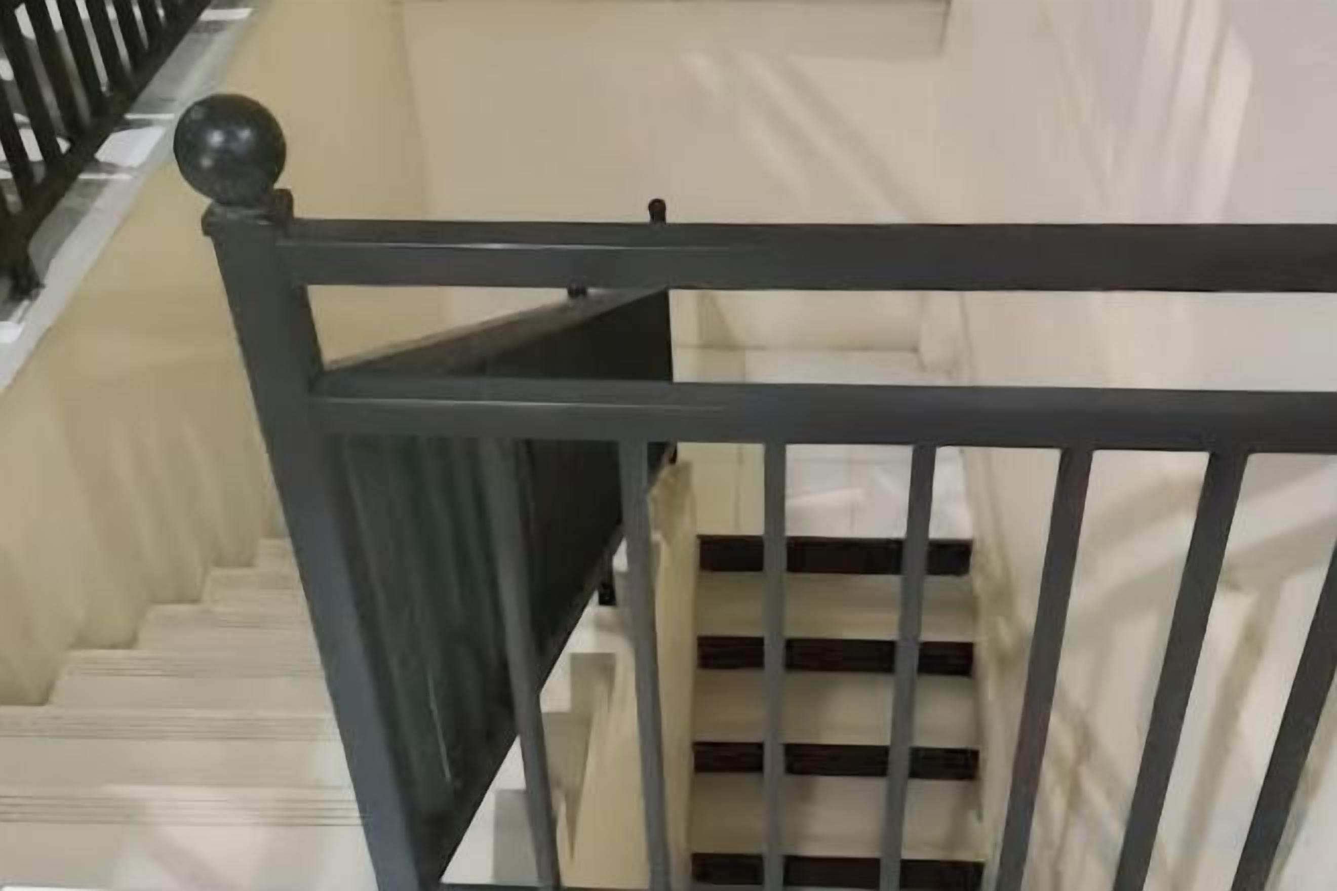 A staircase with a black handrail and white steps.