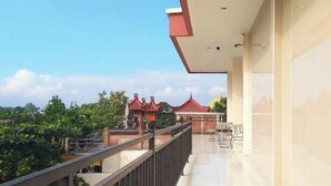 A balcony with a view of traditional buildings and greenery. - Urbanview @ Nalaya Homestay Mataram (East Cakranegara)
