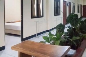 A hallway with a wooden bench, potted plants, and a bed in the background. - Urbanview @ Nalaya Homestay Mataram (East Cakranegara)