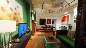 Een woonkamer met een groene bank, een salontafel, een televisie en een schilderij aan de muur.