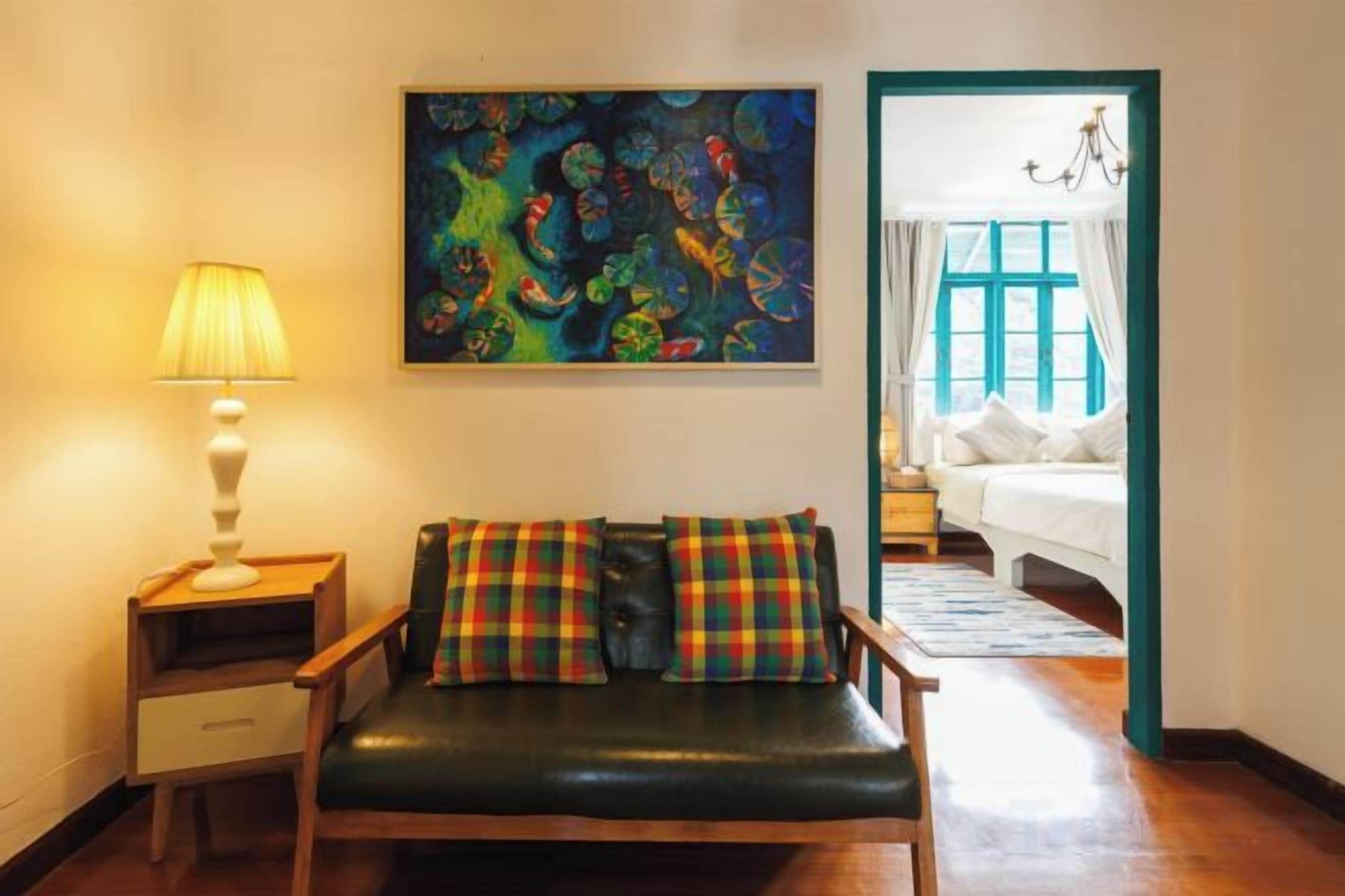 A room with a sofa, a lamp, and a painting on the wall.