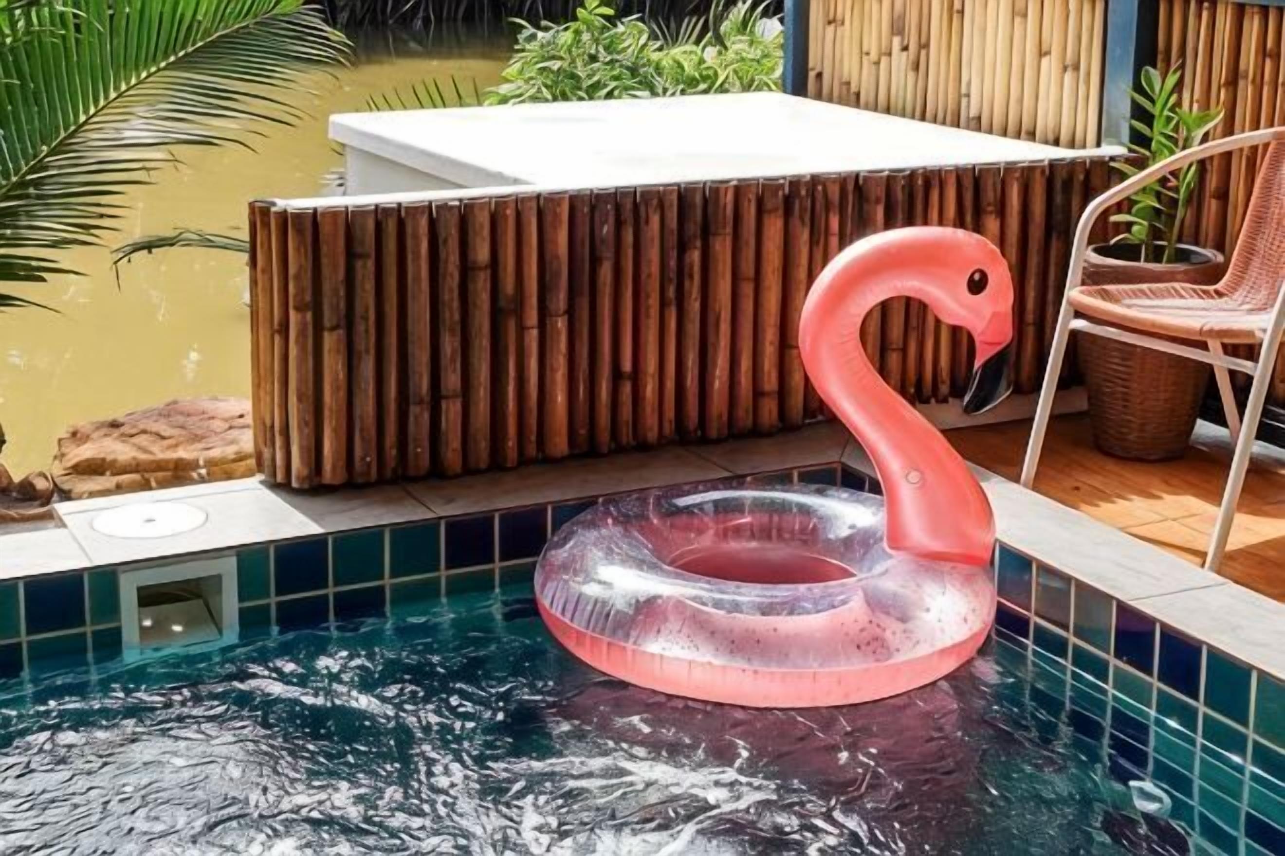 A swimming pool with a pink flamingo float, a wooden deck, and a chair.