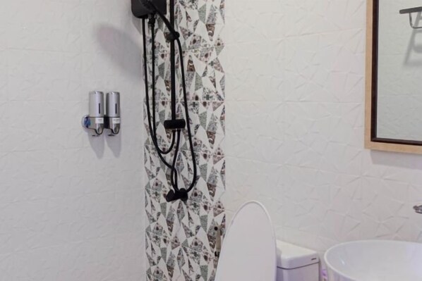 Une salle de bain comprenant des toilettes, un bidet et un lavabo. Il y a deux prises électriques sur le mur.