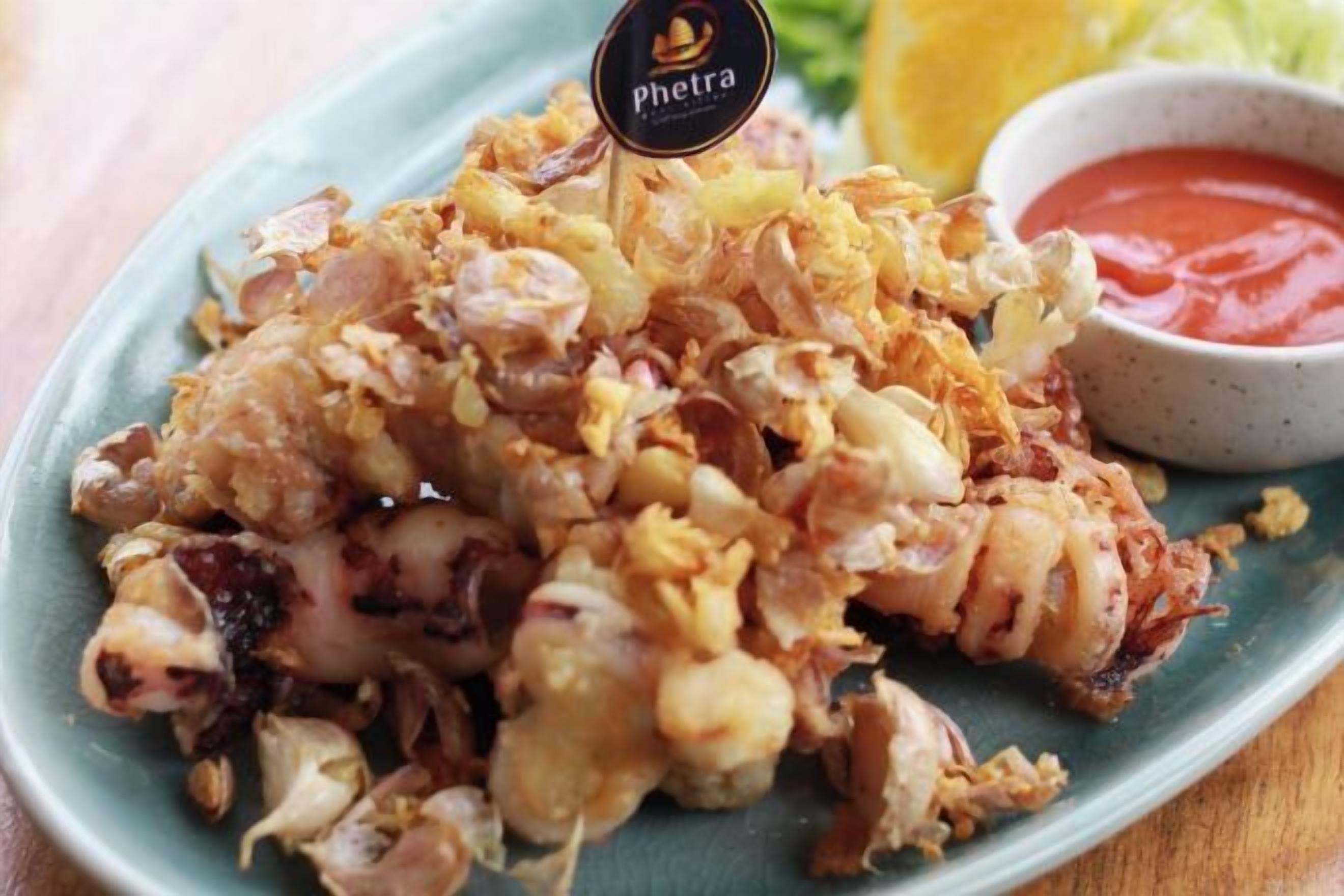 A plate of fried seafood with a side of ketchup.