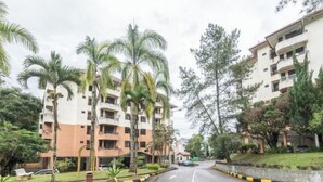 A multi-story residential building with balconies, surrounded by palm trees and other greenery. - Cozy Genting Permai Resort By THM (Genting Highlands)