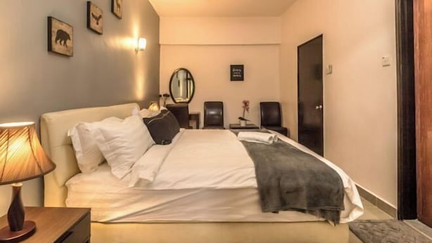 A bedroom with a bed, bedside lamp, wall art, and a door. - Cozy Genting Permai Resort By THM (Genting Highlands)