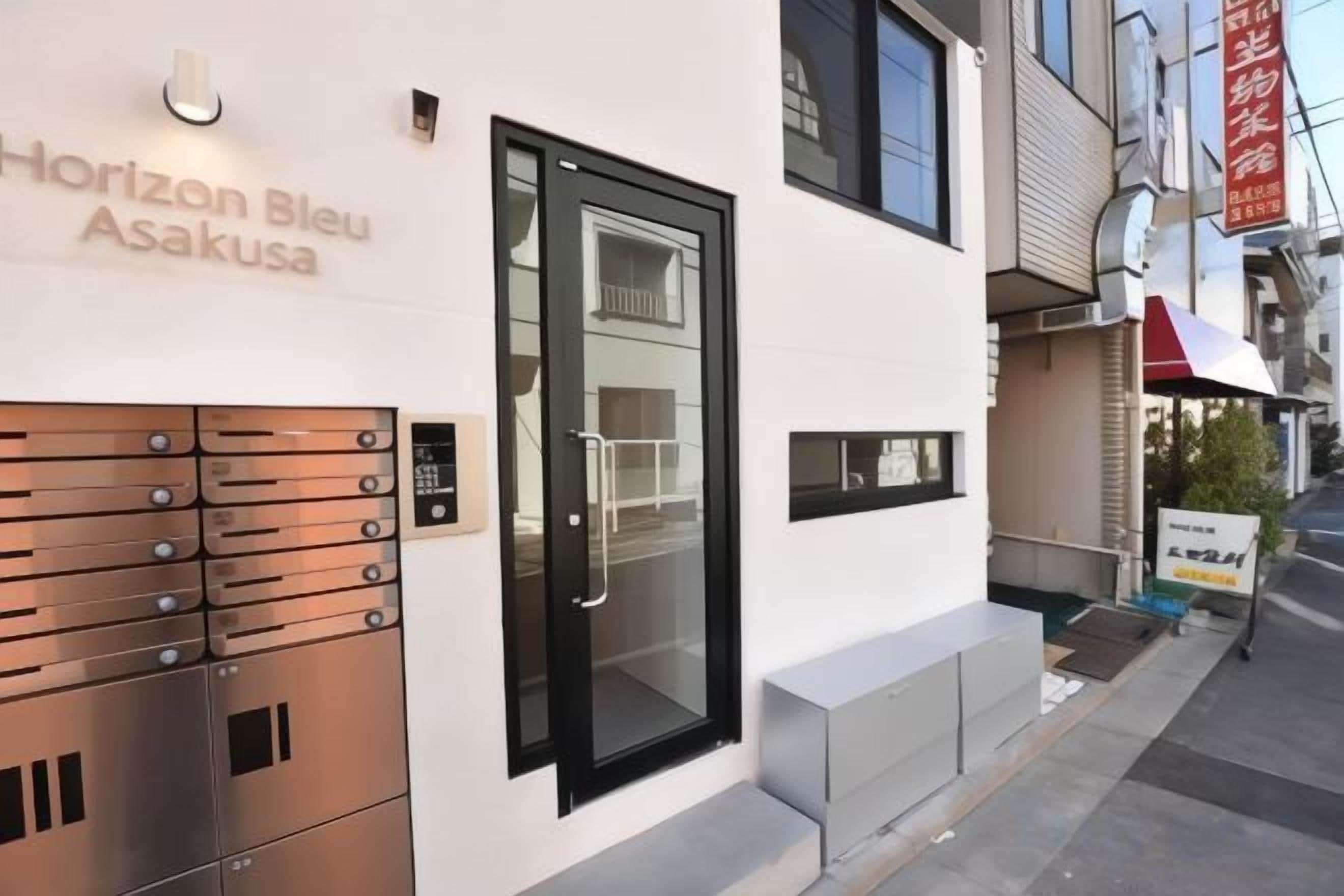 A modern building with a black door and a nameplate reading 'Horizon Bleu Asakusa'.