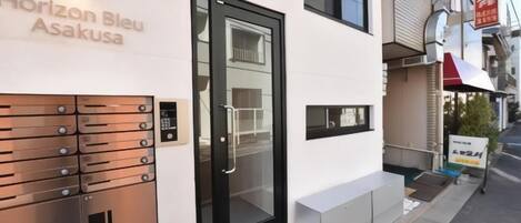 A modern building with a black door and a nameplate reading 'Horizon Bleu Asakusa'.