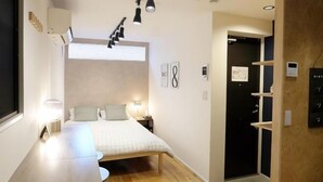 Un dormitorio moderno con cama, mesitas de noche, escritorio y ventana.