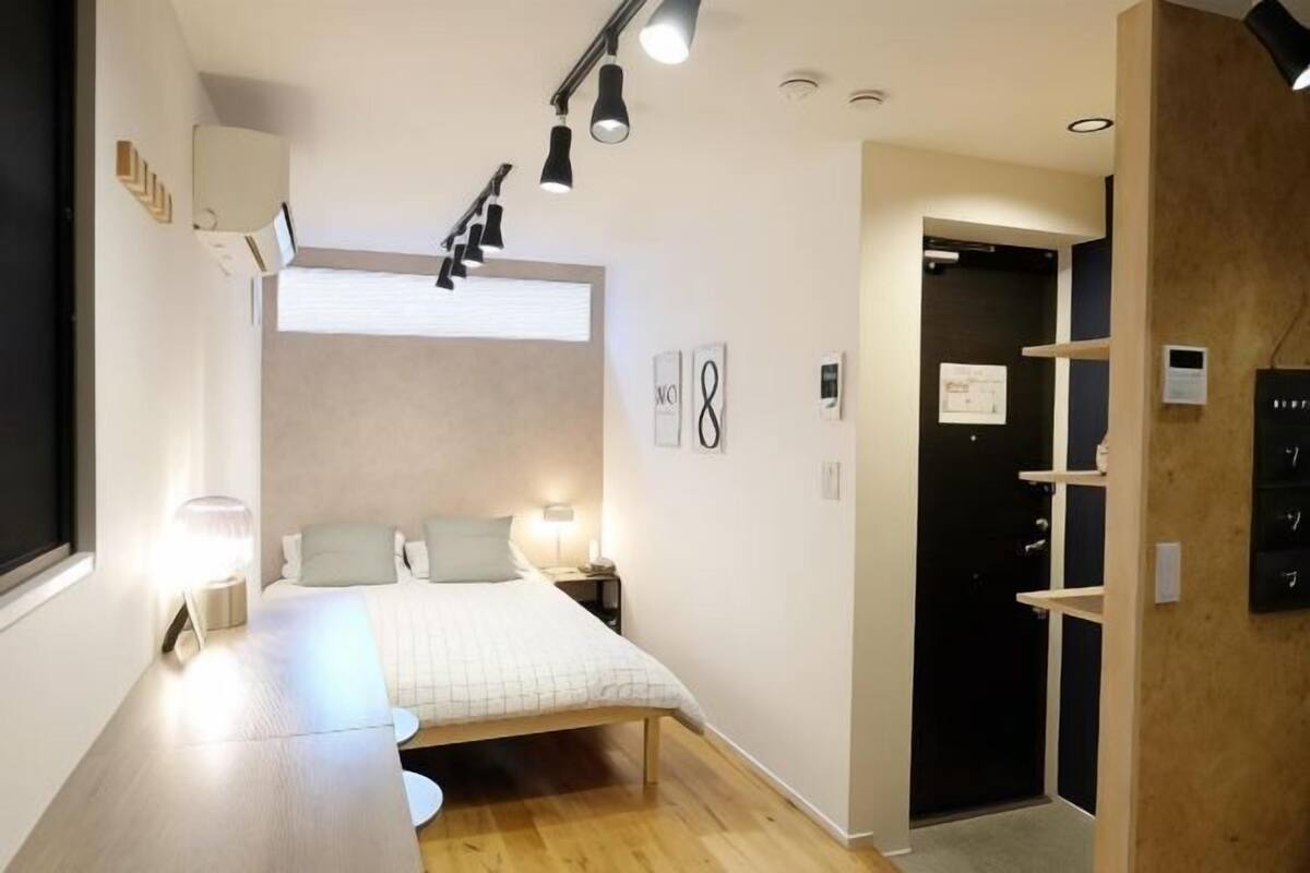 A modern bedroom with a bed, bedside tables, a desk, and a window.