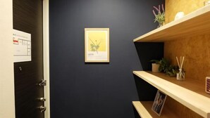 Una habitación oscura con un cuadro enmarcado, estantes de madera con plantas y una puerta con cerradura.