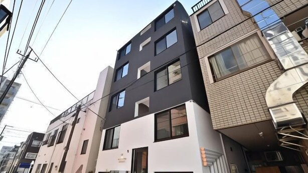 Un edificio de varios pisos con un estilo arquitectónico moderno, que presenta una combinación de techos planos e inclinados, ventanas grandes y una entrada visible con puerta de vidrio.