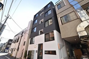 Un immeuble à plusieurs étages, doté d’un style architectural moderne, qui se caractérise par un mélange de toits plats et inclinés, de grandes fenêtres et une entrée bien visible avec une porte en verre.