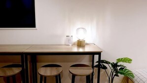 Un comedor con una mesa, sillas, una lámpara fijada en la pared y una planta en maceta.