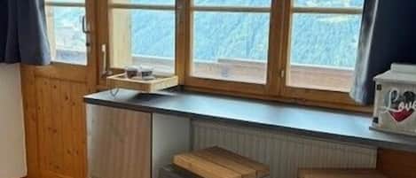 A kitchen with a window, wooden counter, and stools.