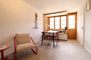 Una habitación pequeña y acogedora con una mesa de comedor, sillas, un sofá y una puerta de madera.