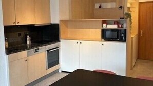 A compact kitchen with a black table and pink chairs, wooden cabinets, and a microwave. - Outside: Bright and warm apartment, facing south, with furnished terrace and exceptional view of the (St-Luc)