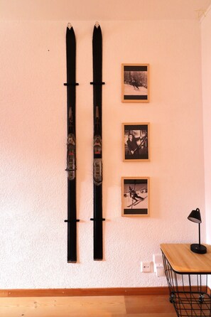 Een muur met twee ski's en drie ingelijste foto's.