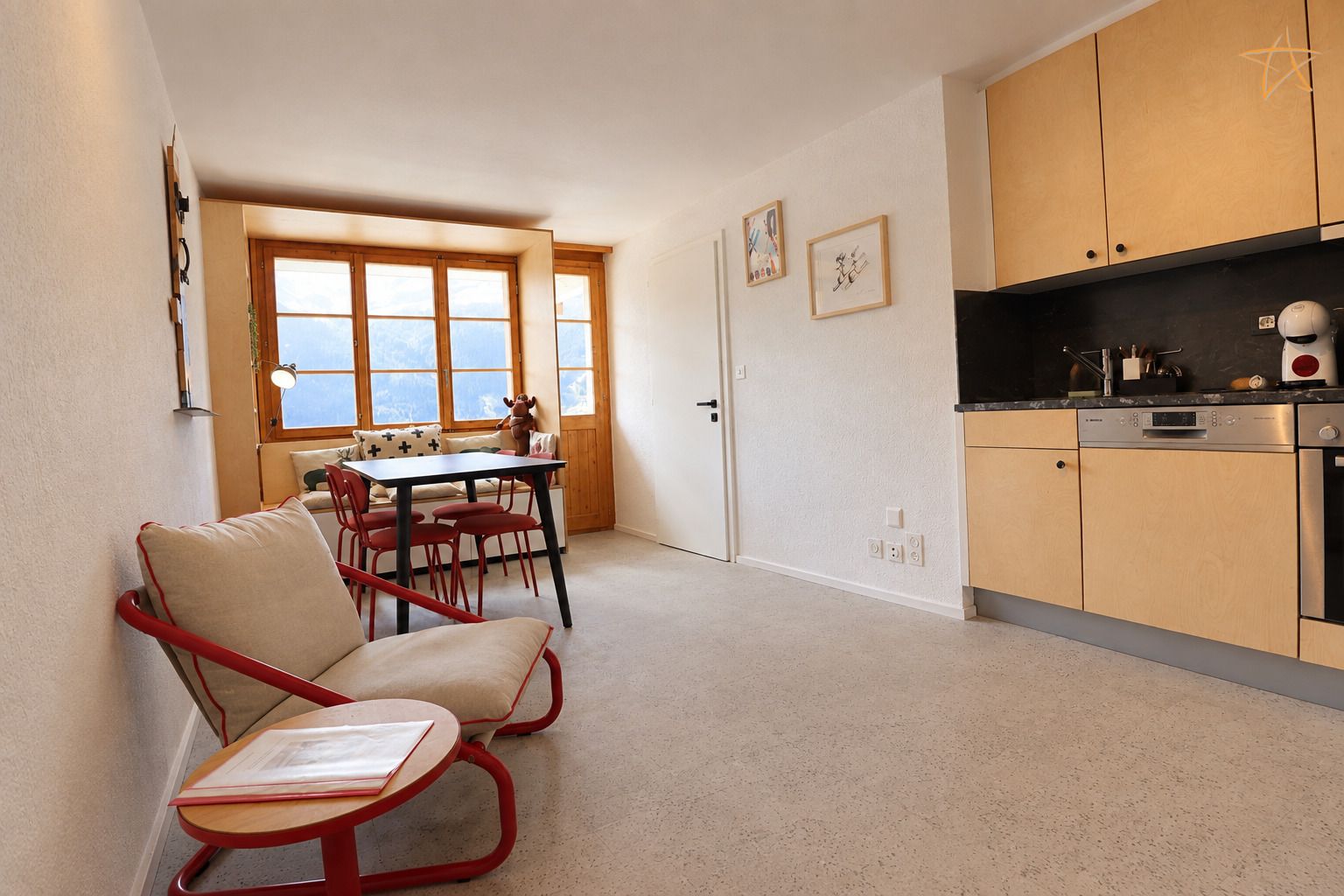 A compact living space with a kitchenette, a dining area with a table and chairs, and a window with a view.