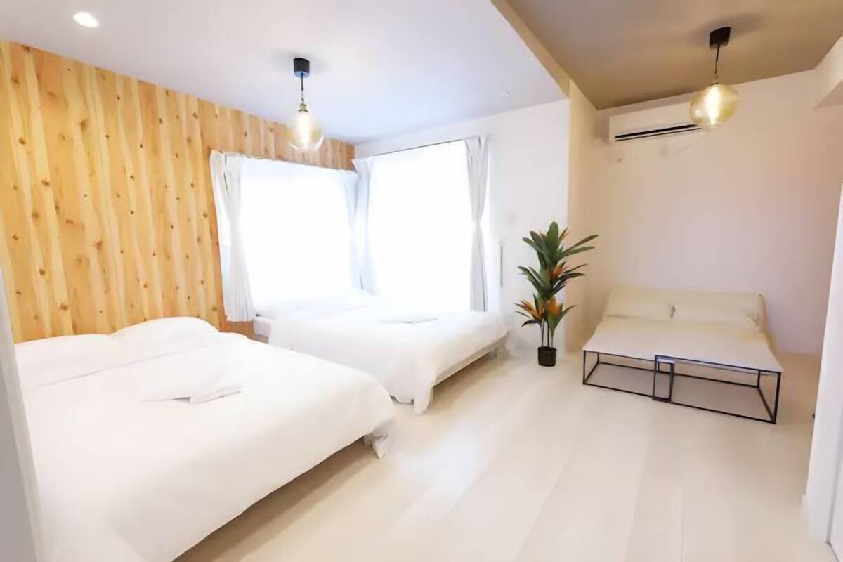 A bedroom with two beds, a potted plant, and a ceiling fan.