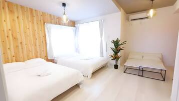 A bedroom with two beds, a potted plant, and a ceiling fan.