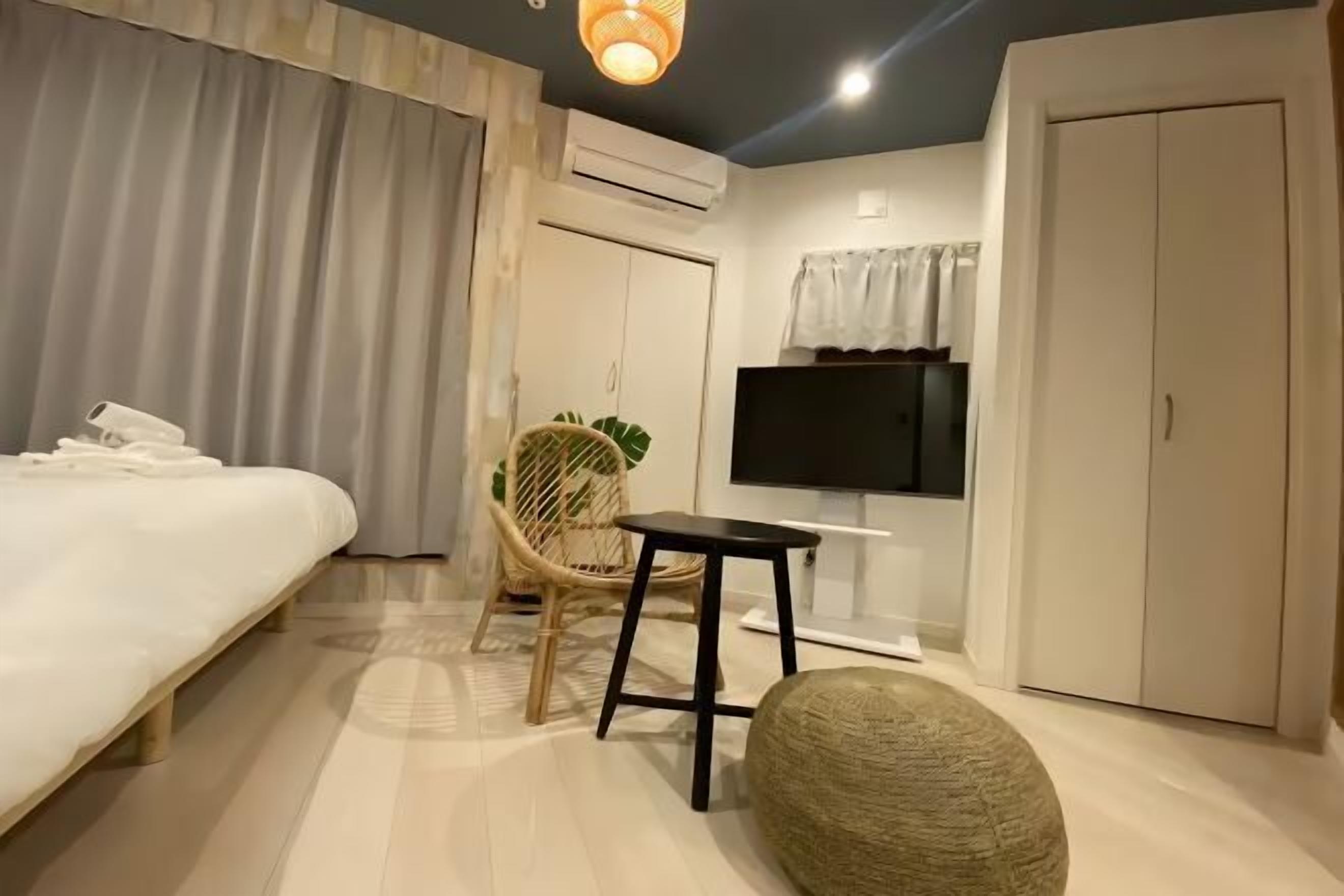 A hotel room with a bed, a chair, a small table, a television, and wardrobes.