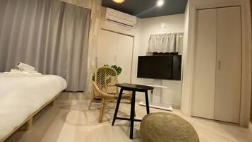 A hotel room with a bed, a chair, a small table, a television, and wardrobes.