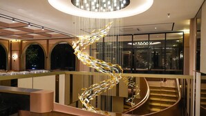 Un intérieur moderne avec un escalier en colimaçon, un lustre central et un coin repas doté d’une longue table.
