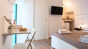 Ein Hotelzimmer mit Bett, Schreibtisch mit Stuhl, Fernseher und einer kleinen Küchenzeile.