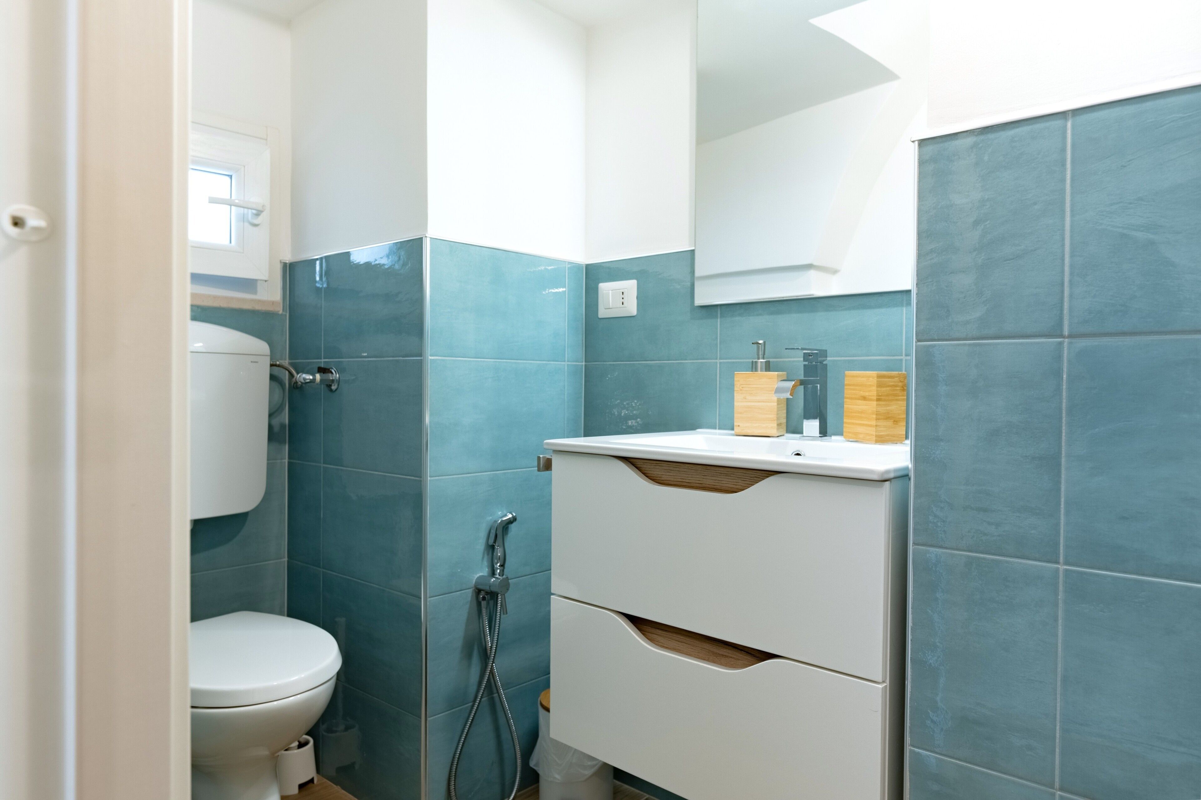 Een badkamer met toilet, douche en wastafel met spiegel erboven.